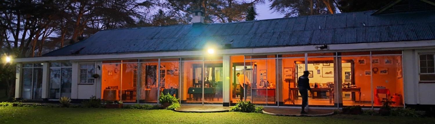 The main house at Elsamere Lodge offers a serene lakeside retreat surrounded by native trees and wildlife.